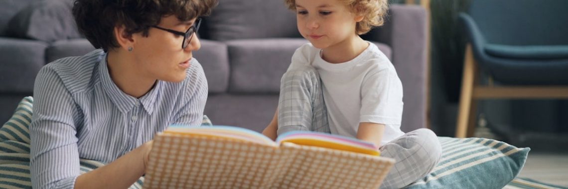 a woman reading a book to a child on the floor